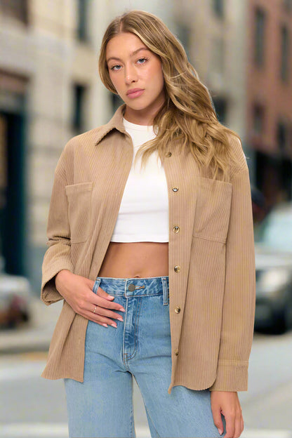 Woman wearing a beige corduroy jacket over a white top and blue jeans on a white background